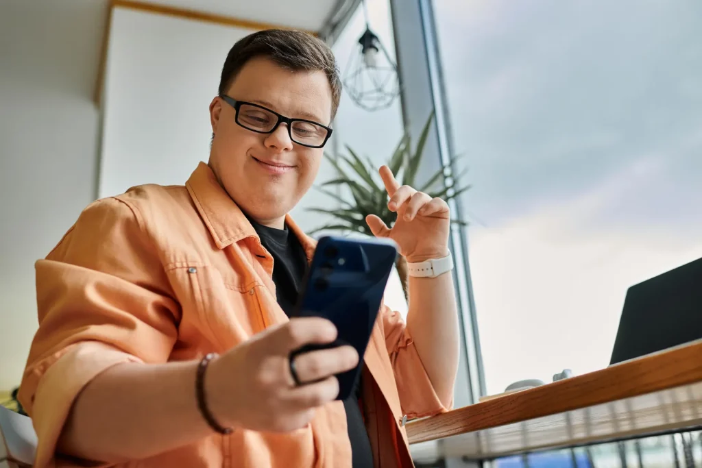 Disabled man smiling, looking down at his phone