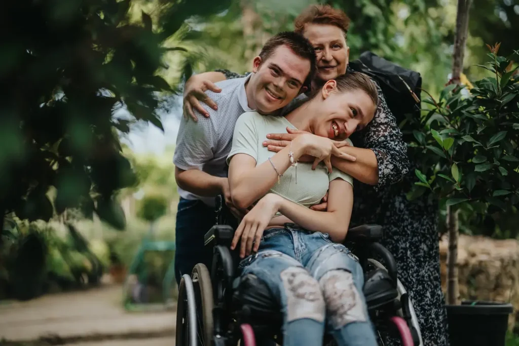 Disabled man, woman, and their carer hugging and smiling
