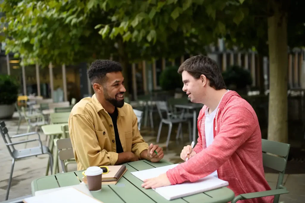 disabled man smiling and having a conversation with his support worker