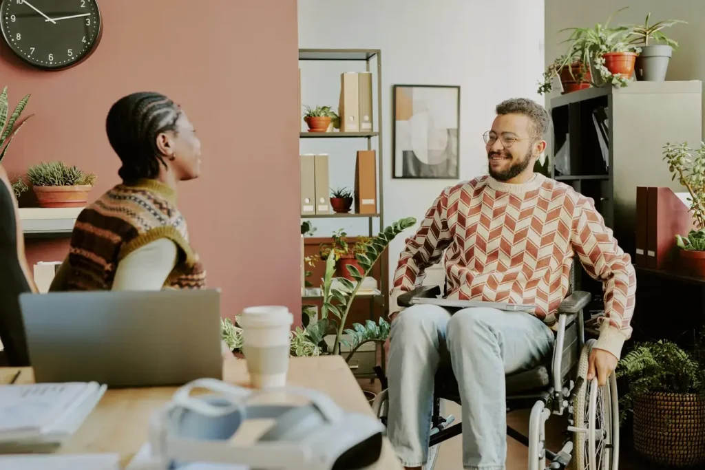 Disabled man in wheelchair talking with support worker in living room