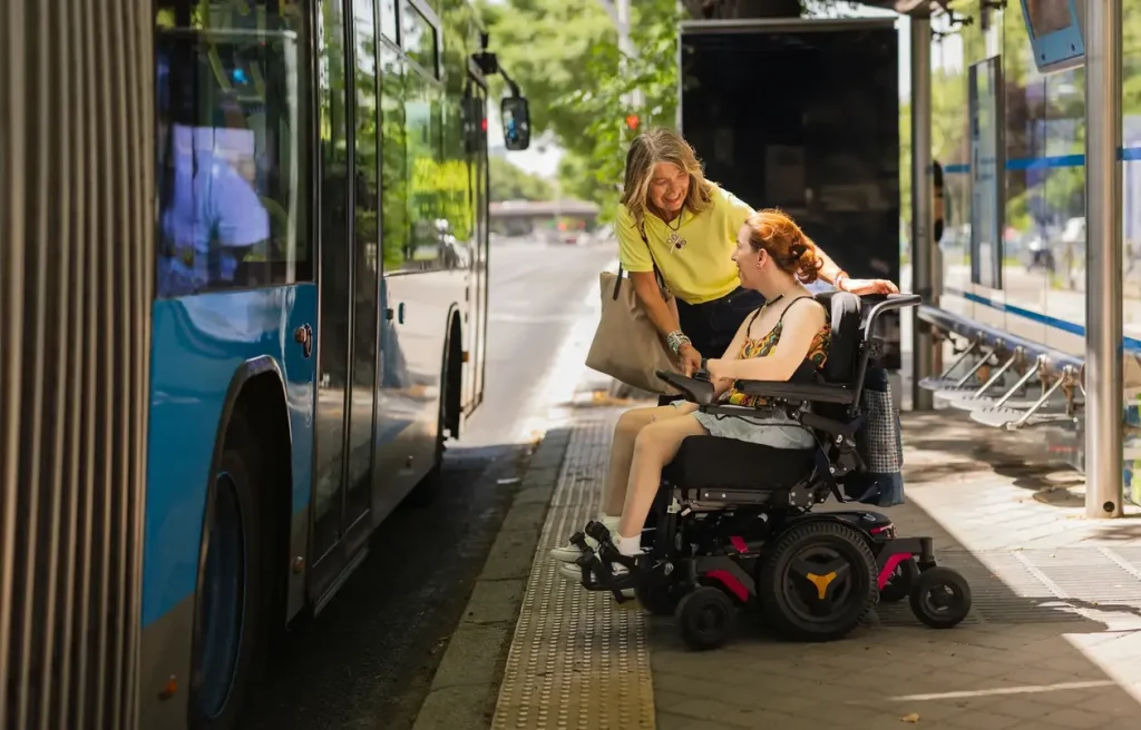 Support worker helping girl in wheelchair enter bus