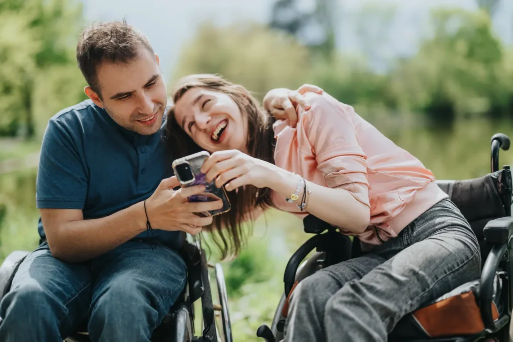 Disabled man and woman smiling while looking at phone
